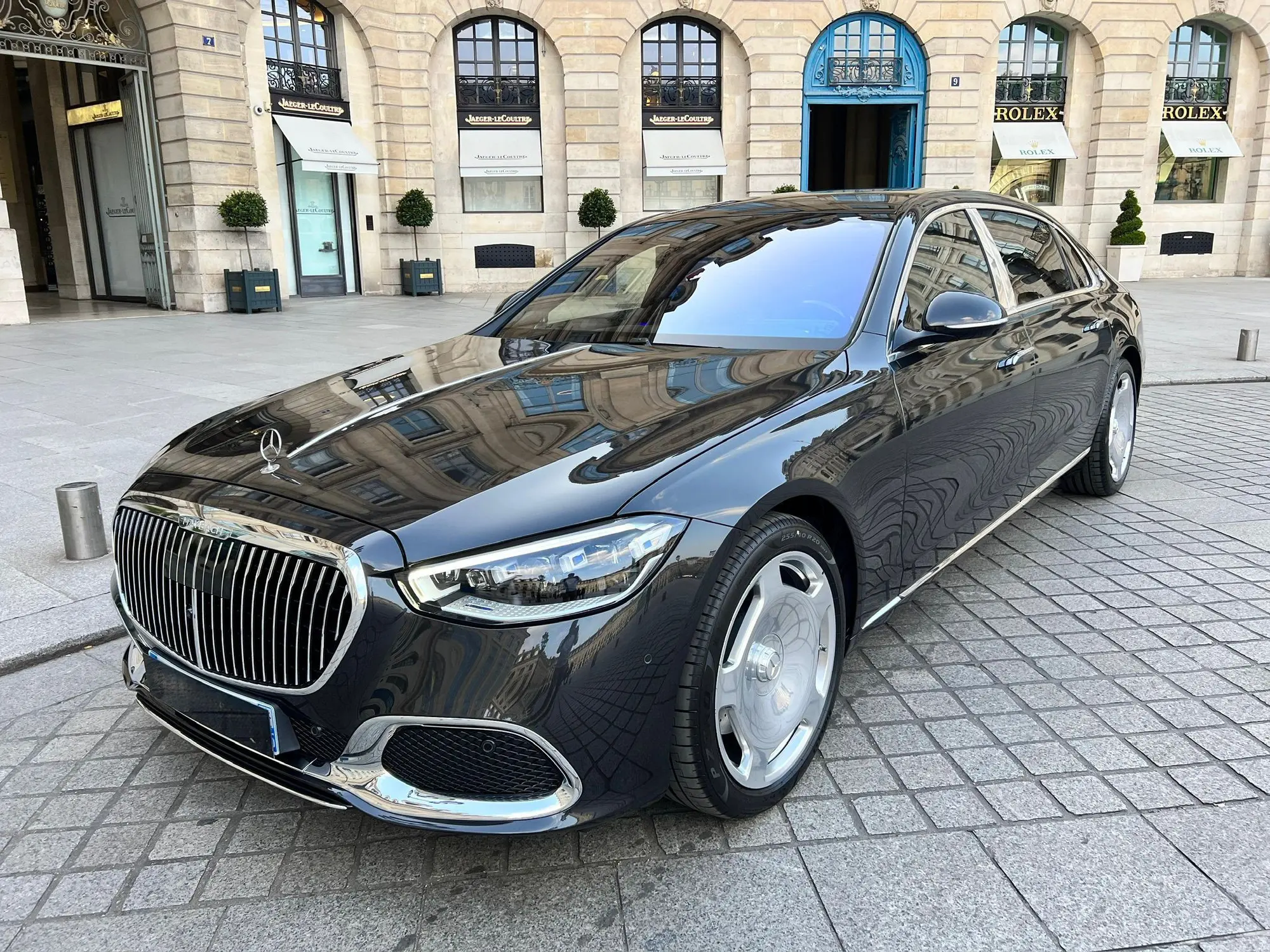 Berline noire avec chauffeur devant des boutiques de luxe