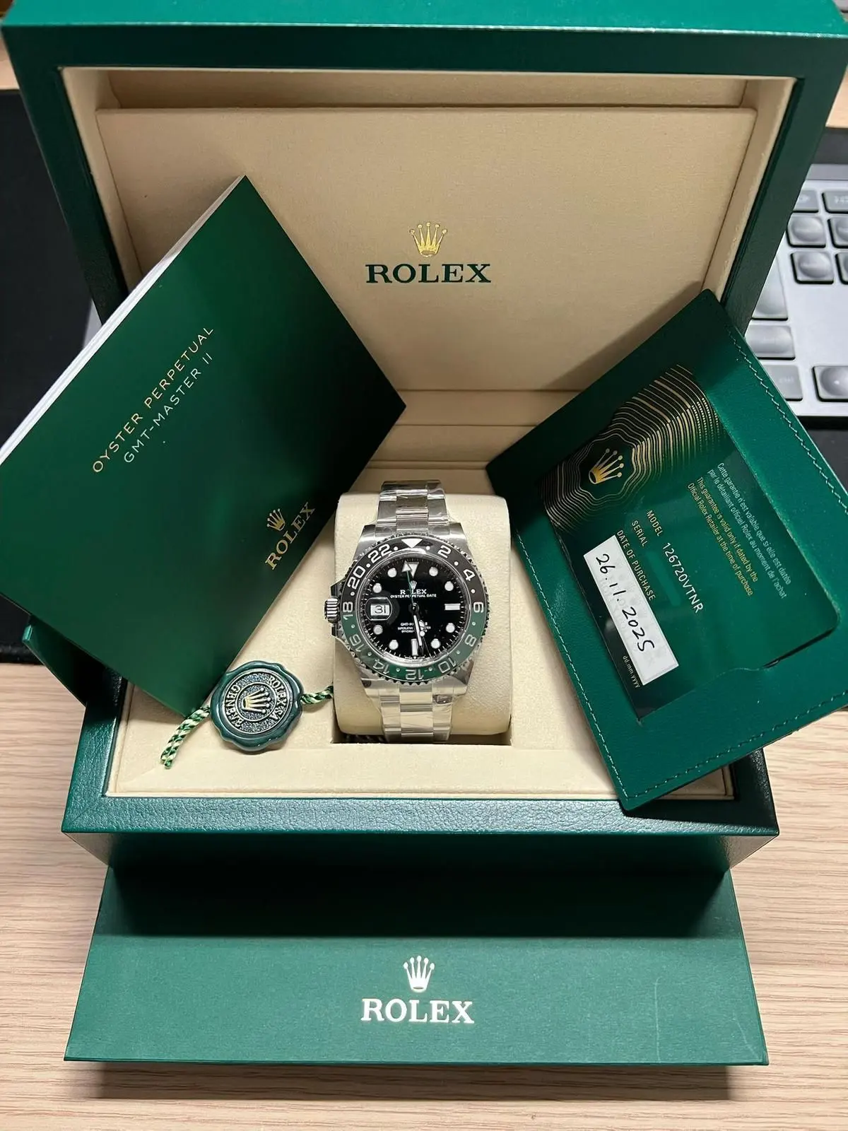 Montre en acier à lunette noire et verte, posée dans son écrin